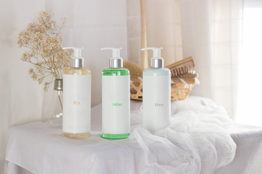 Three bottles with gel, champoo and cream with a brush and a hair comb on a white table in a bathroom