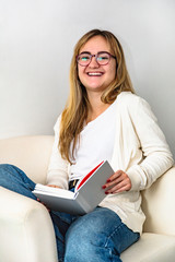 Girl in glasses laughs reading a book fiction at home