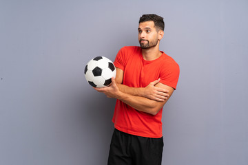 Handsome young football player man over isolated white wall making doubts gesture while lifting the shoulders