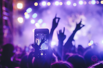 People taking photographs with touch smart phone during a music entertainment public concert