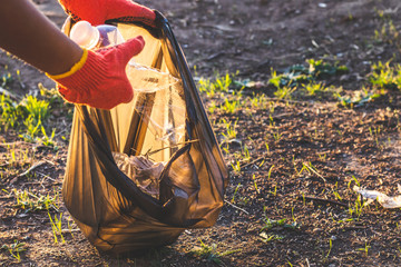 Garbage bottles picked up and thown into a trash bag. Plastic and food waste concept. Clean planet...