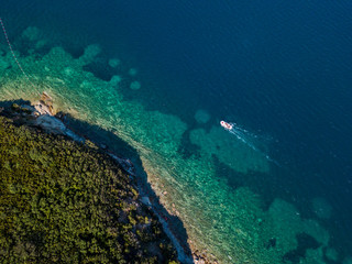 Aerial view of boats and watercraft off the coast of jagged and lush Mediterranean vegetation. Sea, crystal clear water. Sveti Nikola, Budva island, Montenegro