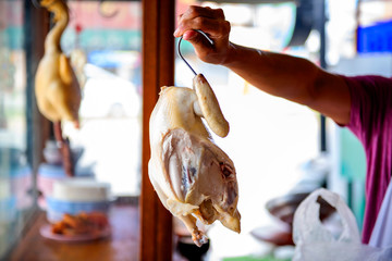 Boiled chicken, located on the chopping board is to be cut to break away for some rice and sauce, steamed chicken and white rice