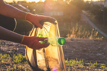 Garbage bottles picked up and thown into a trash bag. Plastic and food waste concept. Clean planet...
