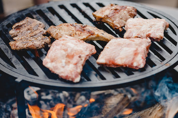 Pork ribs and steak cooked on grill, open fire street food festival