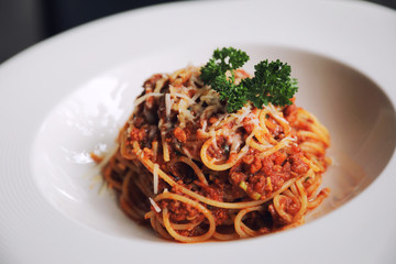 spaghetti Bolognese with minced beef and tomato sauce garnished with parmesan cheese and basil , Italian food