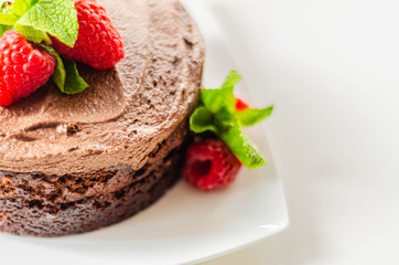 Gluten free tasty round cake based on Belgian chocolate decorated with fresh raspberries and mint
