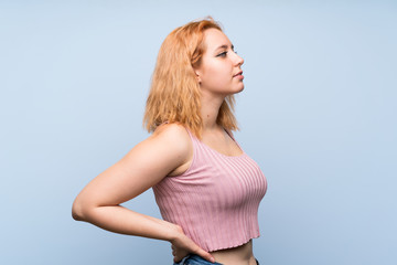 Young woman over isolated blue background suffering from backache for having made an effort