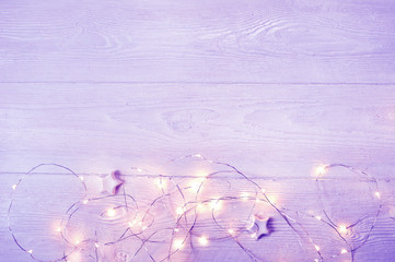Christmas lights garland with stars on lilac background with place for text. Flat lay, copy space