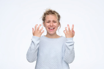 Pretty young blonde girl feeling angry and irritated. Studio shot. Negative facial human emotion