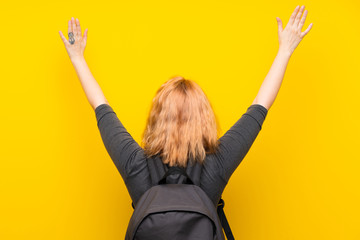 Young woman over isolated yellow background with backpack