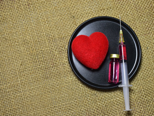 bottle of medicine,Red Heart ,Syringe Put on a cloth of brown sack.