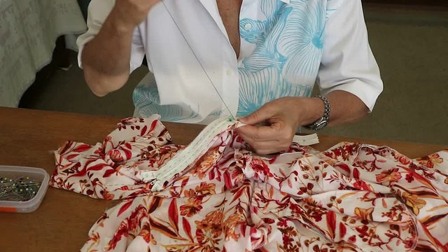 Artesã costureira alinhavando um ziper para depois ser costurado.