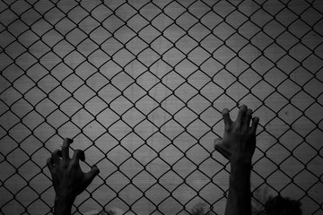 The hand of a male prisoner holding a cage in prison,Hope to be free.