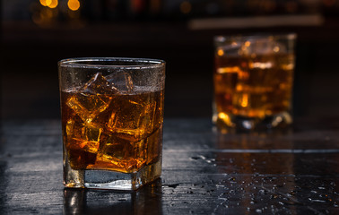 Two Glasses of Whisky (whiskey), bourbon, ice tea or coke (cola) soda with ice and water drops on...