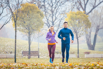 Woman and man running in autumn park for sport