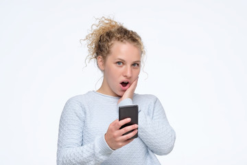 Young curly girl reading a message containing interesting news. Studio shot