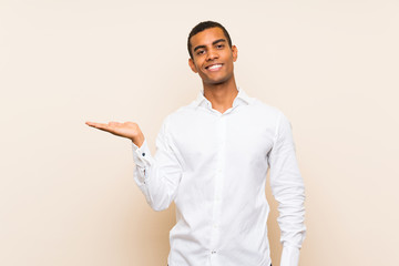 Young handsome brunette man over isolated background holding copyspace imaginary on the palm to...