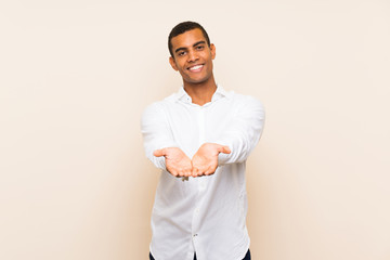 Young handsome brunette man over isolated background holding copyspace imaginary on the palm to...
