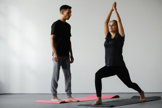Yoga instructor helps young woman to make exercise rigth. Teacher assists to do yoga pose or asana at seminar. Healthy lifestyle in fitness class.