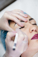Decorative cosmetology. Closeup of female beautician hand applying eyeliner to create contour.