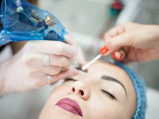 Naklejka premium Decorative cosmetology courses. Female beautician using tattoo machine for eyebrow microblading.