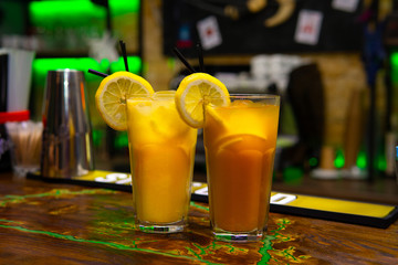 Orange cocktail in a tall glass and a slice of lemon.