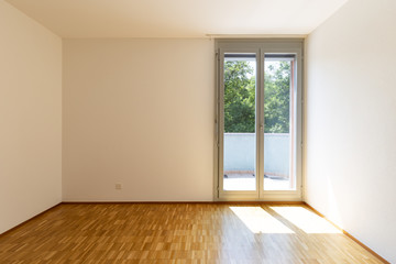 Empty room with white walls and window with balcony.