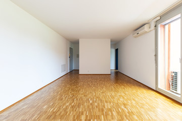 Large empty room with white walls and 70's parquet
