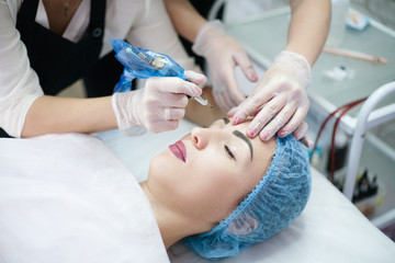 Obraz na płótnie Canvas Eyebrow permanent makeup. Cropped shot of beautician using tattoo machine for microblading.