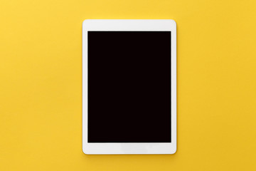 top view of digital tablet with blank screen on yellow background