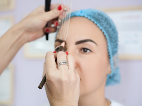 Permanent makeup. Professional female artist measuring eyebrow to create perfect design.