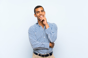 Young handsome brunette man over isolated blue background thinking an idea while looking up