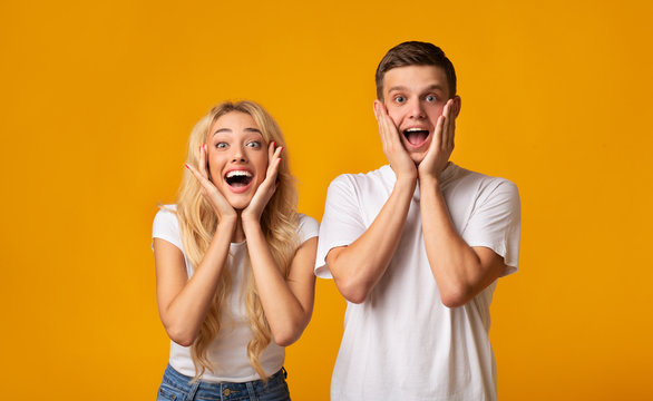 Excited young couple opening mouths and touching cheeks in amazement
