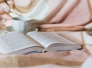 a Cup of coffee and an open book on the background of a warm blanket