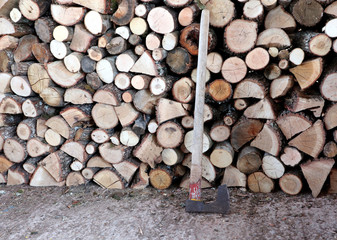 Pile of firewood and wooden logs and axe. Preparation and storage for the winter. 