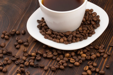 Cup of coffee surrounded by coffee beans.