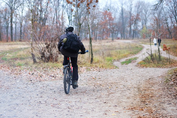 Sport and active healthy life concept. Cyclist in protective late fall forest. Riding on bike on sunny day among many trees.