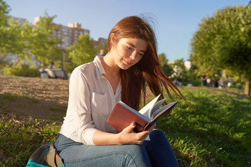 Obraz premium Pretty Caucasian student reads notes in city park