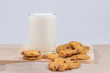Cookies and fresh milk placed on a wooden plate on a white background, break snacks, chocolate chip cookies