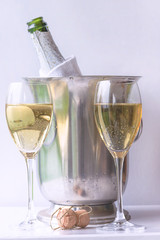Two glasses and bottle of champagne in the bucket on the white background, vertical picture