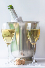 Two glasses and bottle of champagne in the bucket on the white background, vertical picture