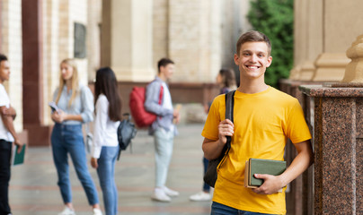 College student smiling to camera, standing against friends