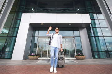 Happy man arrived home, waving hand while going out of airport building