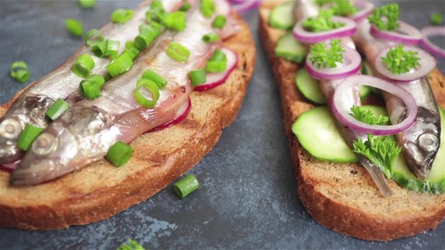 open sandwiches with small fish capelin cucumber radish grilled bread onion panning shot