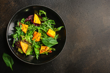 healthy salad pumpkin, mix leaves (tasty snack, vitamins, wholesome food) menu concept. food background. copy space. Top view
