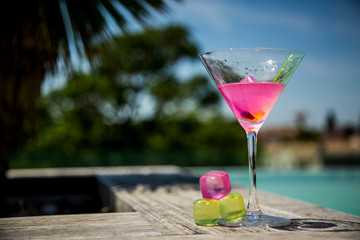 Cocktail rose au bord d'une piscine en rooftop