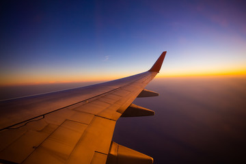 Fototapeta na wymiar Airplane wing with sunrise in light flare