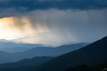 sun ray through thunderstorm clouds in the mountains