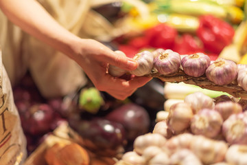 Zero waste, plastic free concept. Sustainable lifestyle. Woman chooses fruits and vegetables at farmers market. Reusable cotton and mesh eco bags for shopping.